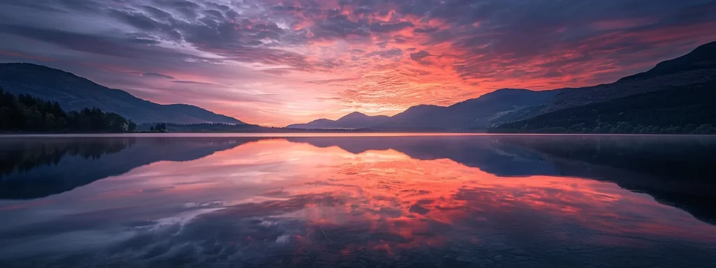 a serene sunrise illuminates a tranquil lake, creating a breathtaking mirror effect as vibrant hues of orange and pink reflect off the still water, surrounded by majestic mountains.
